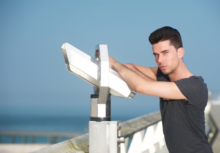 Portrait of an attractive man leaning on telescope on tourism pierの写真素材