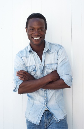 Portrait of a casual guy smiling with arms crossed against white backgroundの写真素材