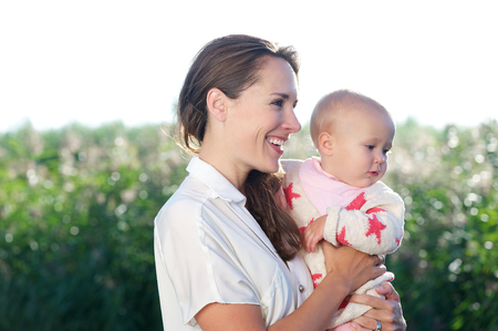 Closeup portrait of beautiful mother smiling and holding cute babyの写真素材