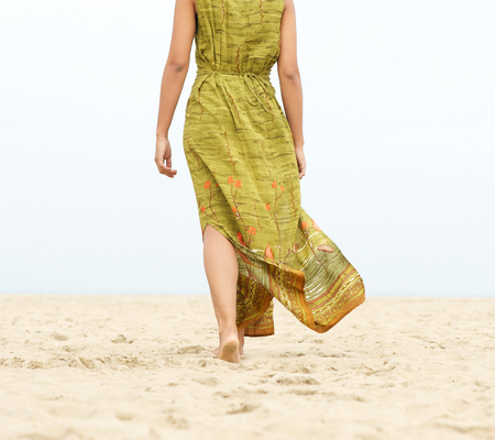 Portrait of a woman walking barefoot at the beach - from behindの写真素材