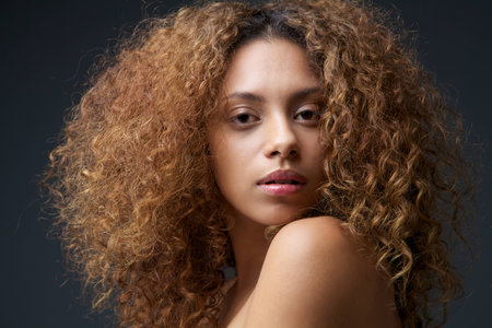 Close up beauty portrait of a beautiful female fashion model with curly hairの写真素材