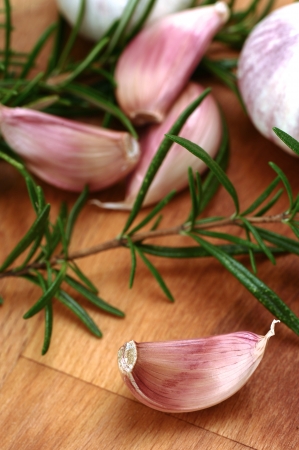 Close up garlic and rosemary on a wooden chopping boardの写真素材