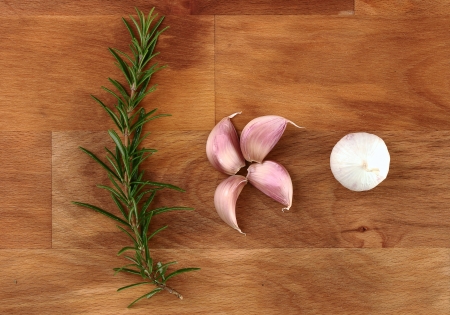 Close up group of garlic cloves and fresh organic rosemary on wooden chopping boardの写真素材