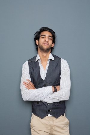 Portrait of a casual young businessman posing with arms crossed against gray backgroundの写真素材
