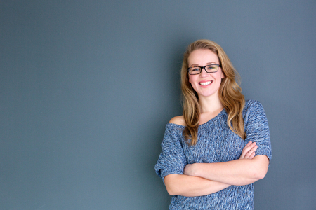 Close up portrait of a business woman standing against gray background with arms crossed Close up portrait of a business woman standing against gray background with arms crossed