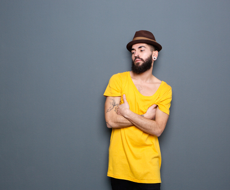 Portrait of a young man standing alone with arms crossed on gray backgroundの写真素材