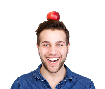 Close up portrait of a smiling man balancing apple on head isolated white backgroundの写真素材