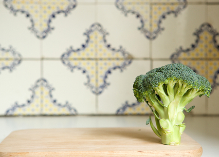 Close up of one broccoli on wooden chopping board in kitchen. Copy spaceの写真素材