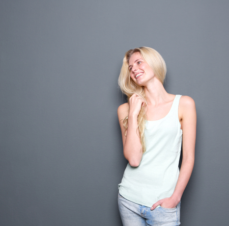 Portrait of a cheerful young blond woman smiling smiling on gray backgroundの写真素材