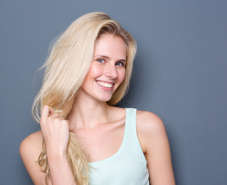 Close up portrait of a beautiful blond hair woman smiling on gray backgroundの写真素材