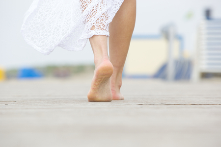 Close up low angle barefoot woman walking awayの写真素材