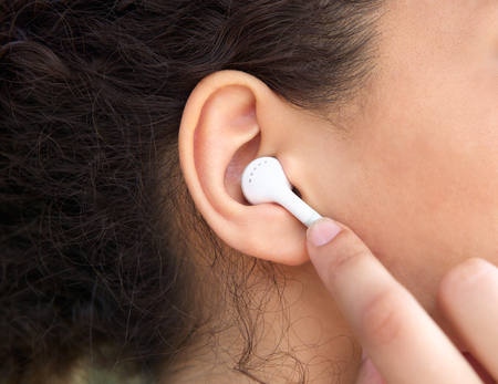 Close up young female ear with earphone 