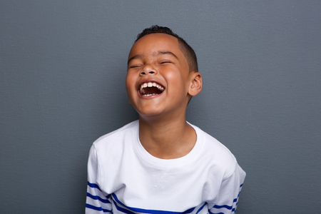 Close up portrait of an excited little boy laughing on gray backgroundの写真素材
