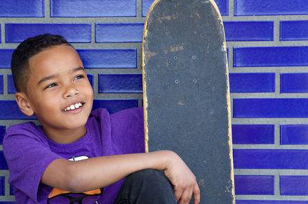 Close up portrait of a cute kid smiling outdoors with skateboardの写真素材
