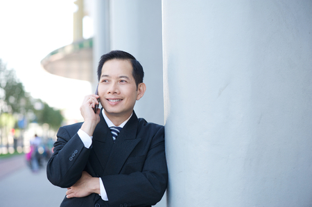 Close up portrait of a smiling businessman with mobile phoneの写真素材