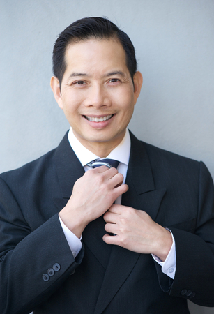 Close up portrait of a smiling businessman holding necktieの写真素材