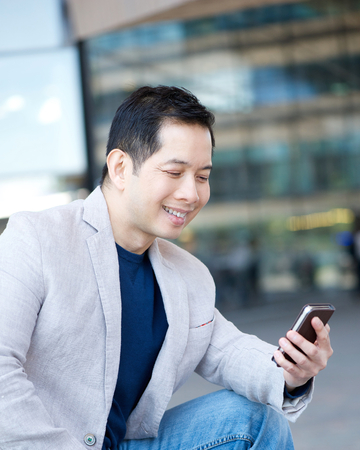 Portrait of an asian man smiling with mobile phoneの写真素材