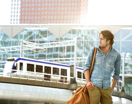 Portrait of a fashionable young man traveling with leather bagの写真素材