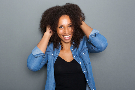 Close up portrait of a cheerful, carefree woman smiling with hand in hairの写真素材