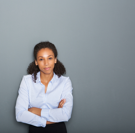 Close up portrait of a female business person with arms crossed on gray backgroundの写真素材