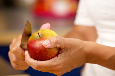 Close up female hands slicing apple with knifeの写真素材