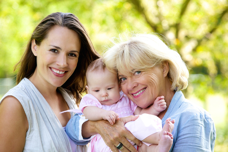 Portrait of a mother and grandmother smiling with baby outdoors