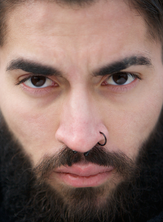 Close up man face with beard and nose piercing