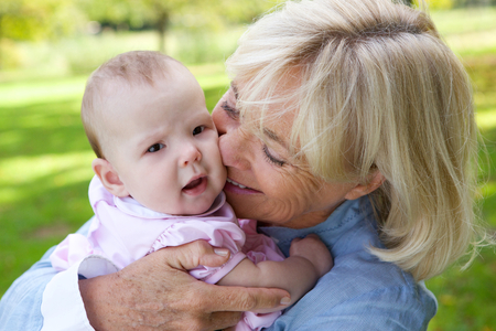 Close up portrait of a happy grandmother holding cute babyの写真素材