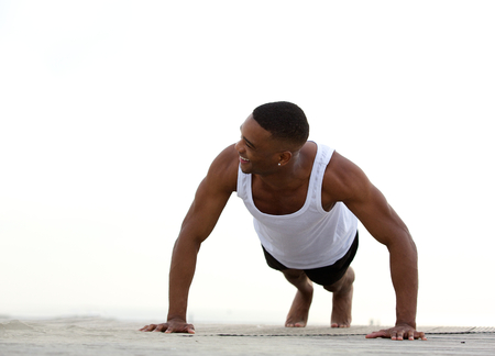 Portrait of a young athletic man smiling and doing push ups