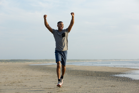 Man running on beach with arms outstretched celebratingの写真素材