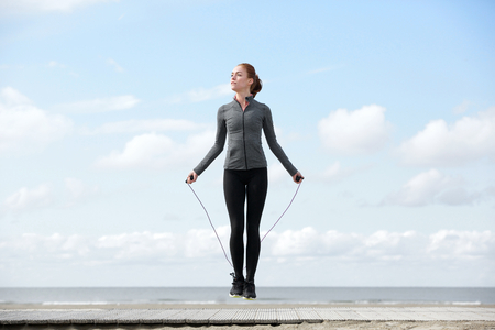 Sporty woman warming up with jump rope outdoorsの写真素材