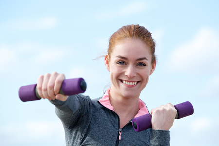 Young woman smiling with aerobic weights outdoorsの写真素材