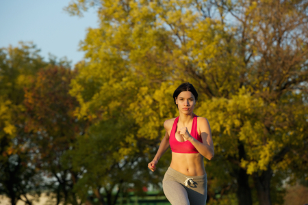 Horizontal portrait of an attractive young woman running outdoors in the parkの写真素材