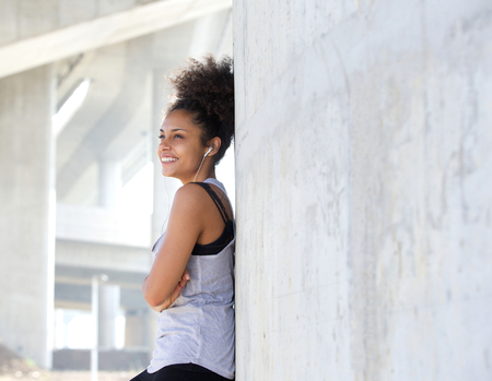 Close up portrait of a happy attractive young black woman listening to music with earphonesの写真素材