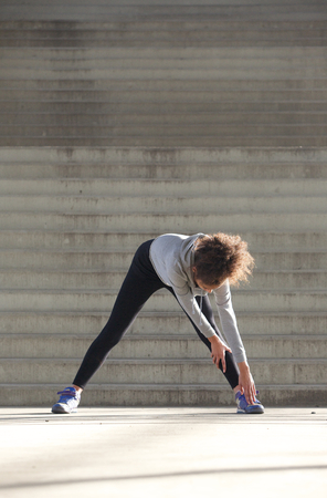 Portrait of a young woman bending down stretching leg musclesの写真素材
