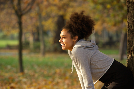 Portrait of a young woman smiling and resting after workout in the parkの写真素材
