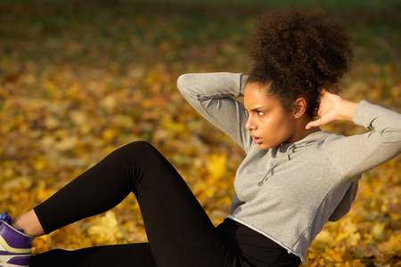 Portrait of a young woman exercising sit ups outdoorsの写真素材