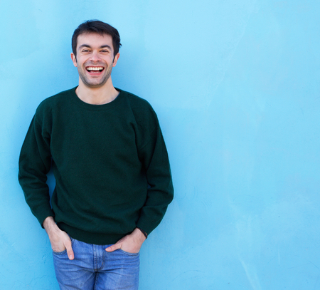 Portrait of an friendly young man smiling against blue backgroundの写真素材