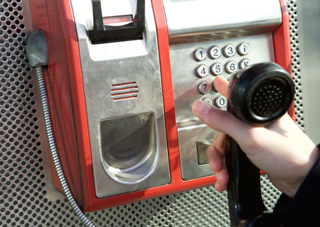 Close up hand pushing buttons at public phone