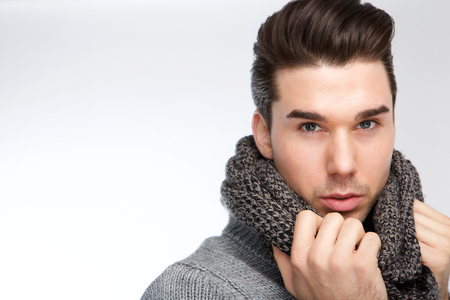 Close up portrait of a trendy young man posing with gray wool scarfの写真素材