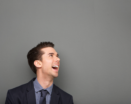 Portrait of a happy young business man laughing on gray backgroundの写真素材