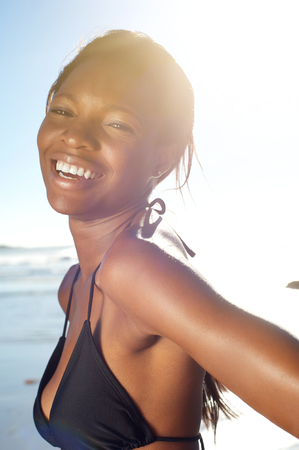 Close up portrait of a happy african american woman at the beach in bikiniの写真素材