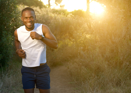 Portrait of a happy young sports man running outdoorsの写真素材