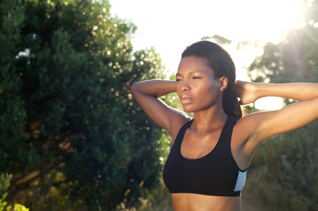 Close up portrait of an attractive african american fitness model with hands behind headの写真素材