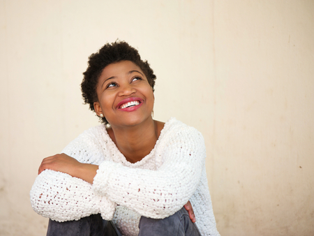 Close up portrait of a happy young black woman smiling and looking upの写真素材