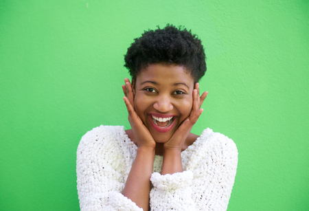 Close up portrait of a surprised young woman smiling with hands on face