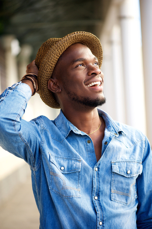 Portrait of a carefree young african american man smiling with hatの写真素材