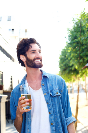 Portrait of a relaxed casual man smiling with glass of beerの写真素材