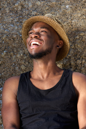 Close up portrait of a happy young man laughing with hatの写真素材