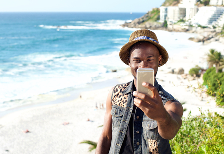 Portrait of a happy african american man on vacation taking selfieの写真素材